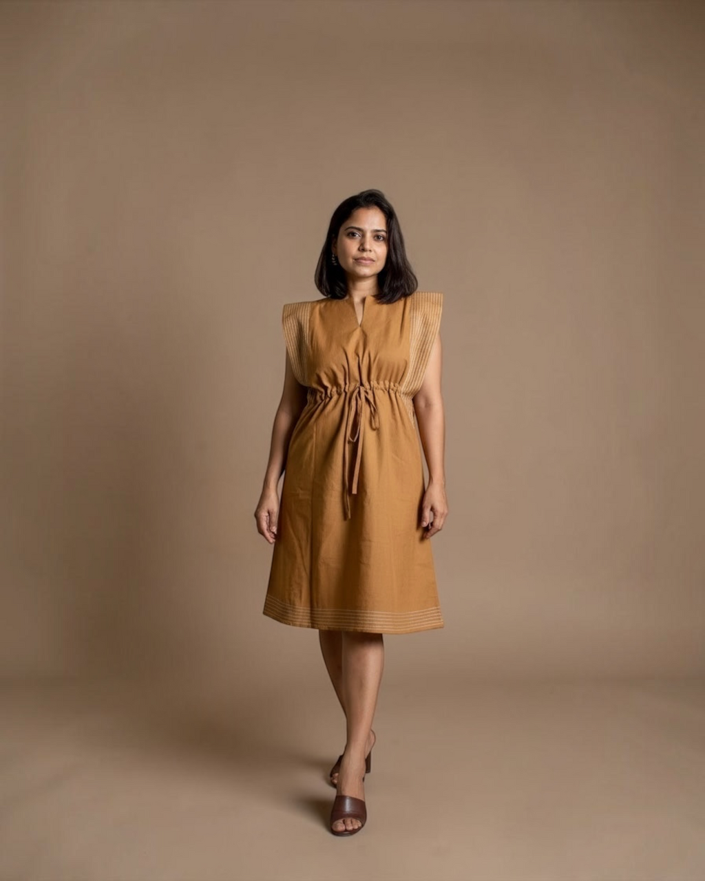 Model wearing camel drawstring midi dress with pintuck shoulder detailing