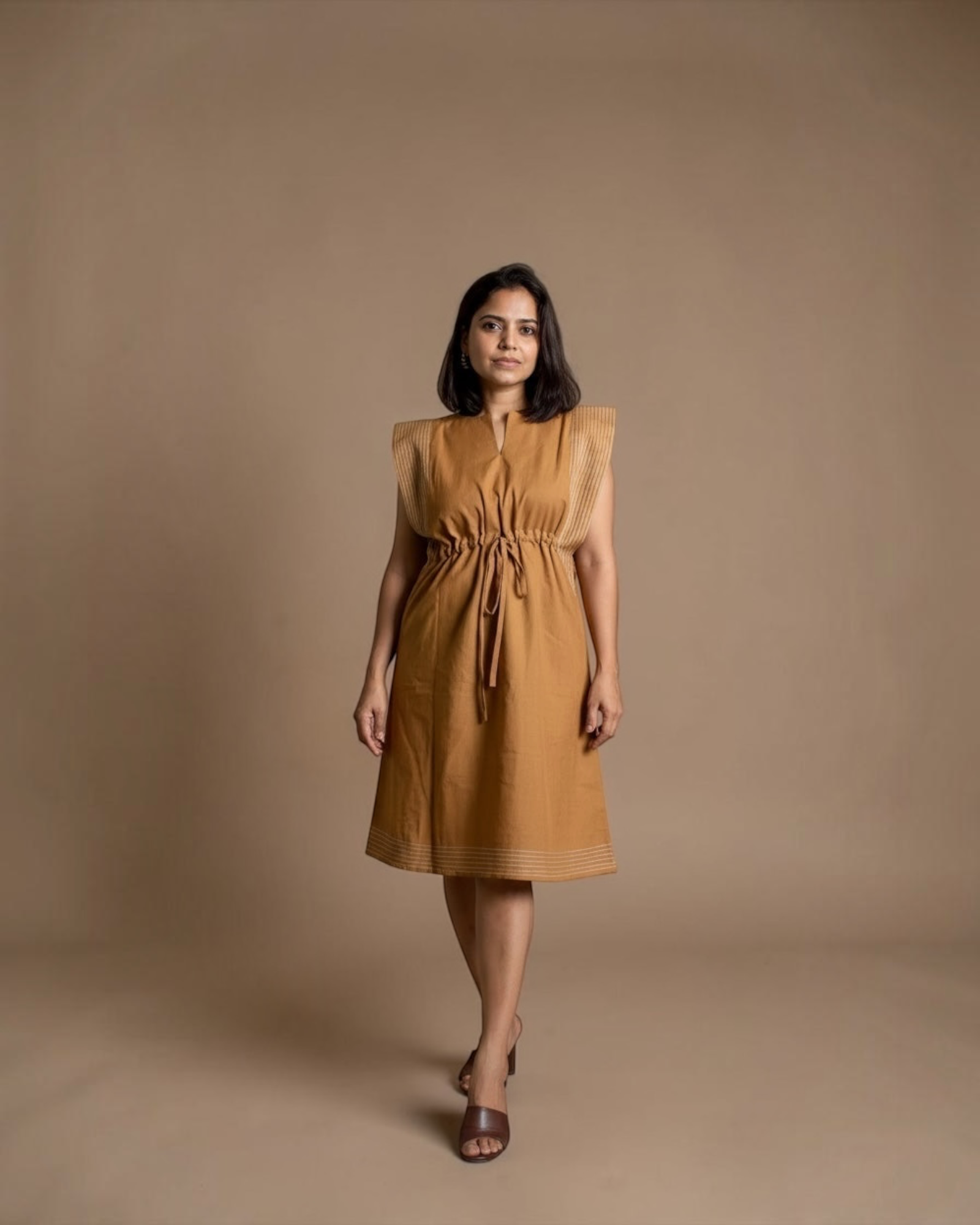 Model wearing camel drawstring midi dress with pintuck shoulder detailing