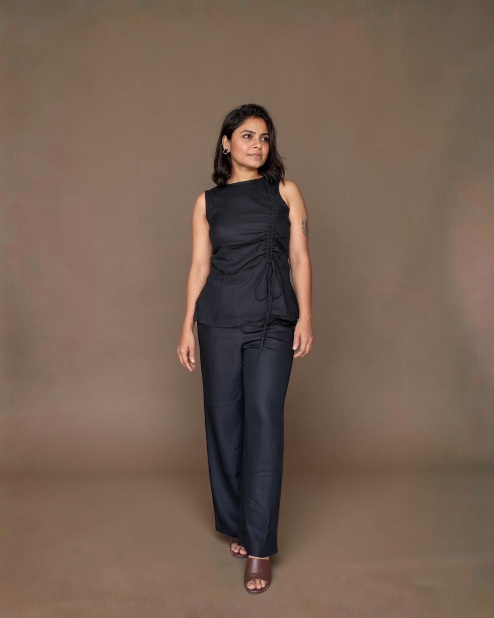 Model wearing black ruched sleeveless top with wide-leg trousers, front view
