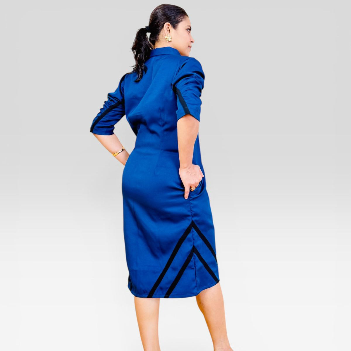 Woman wearing a blue dress with black accents on a white background