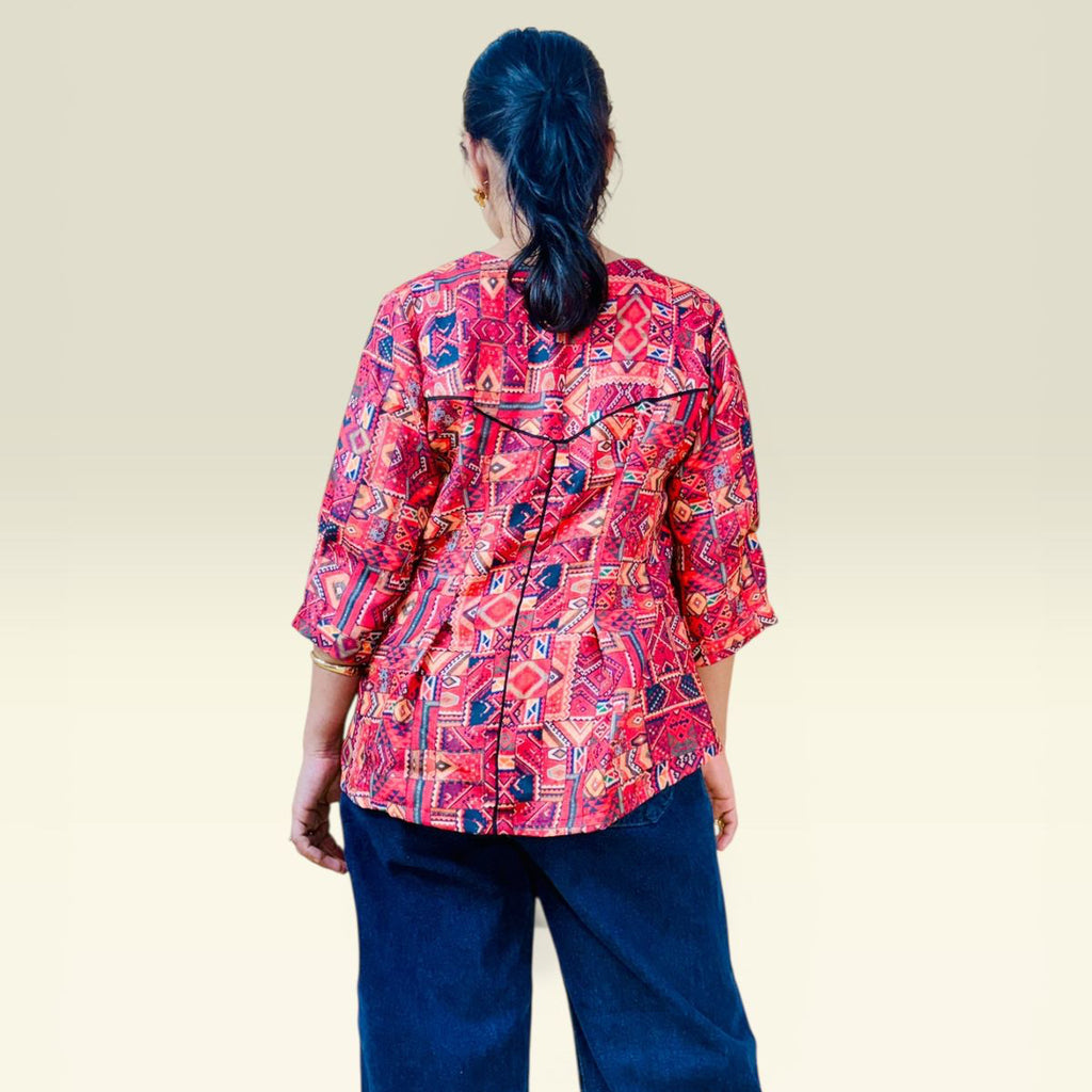 Person wearing a red patterned shirt and blue pants on a beige background