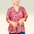 Woman wearing a red patterned blouse against a plain background